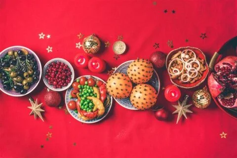 Festive table setting with seasonal foods and decorations on a red background.